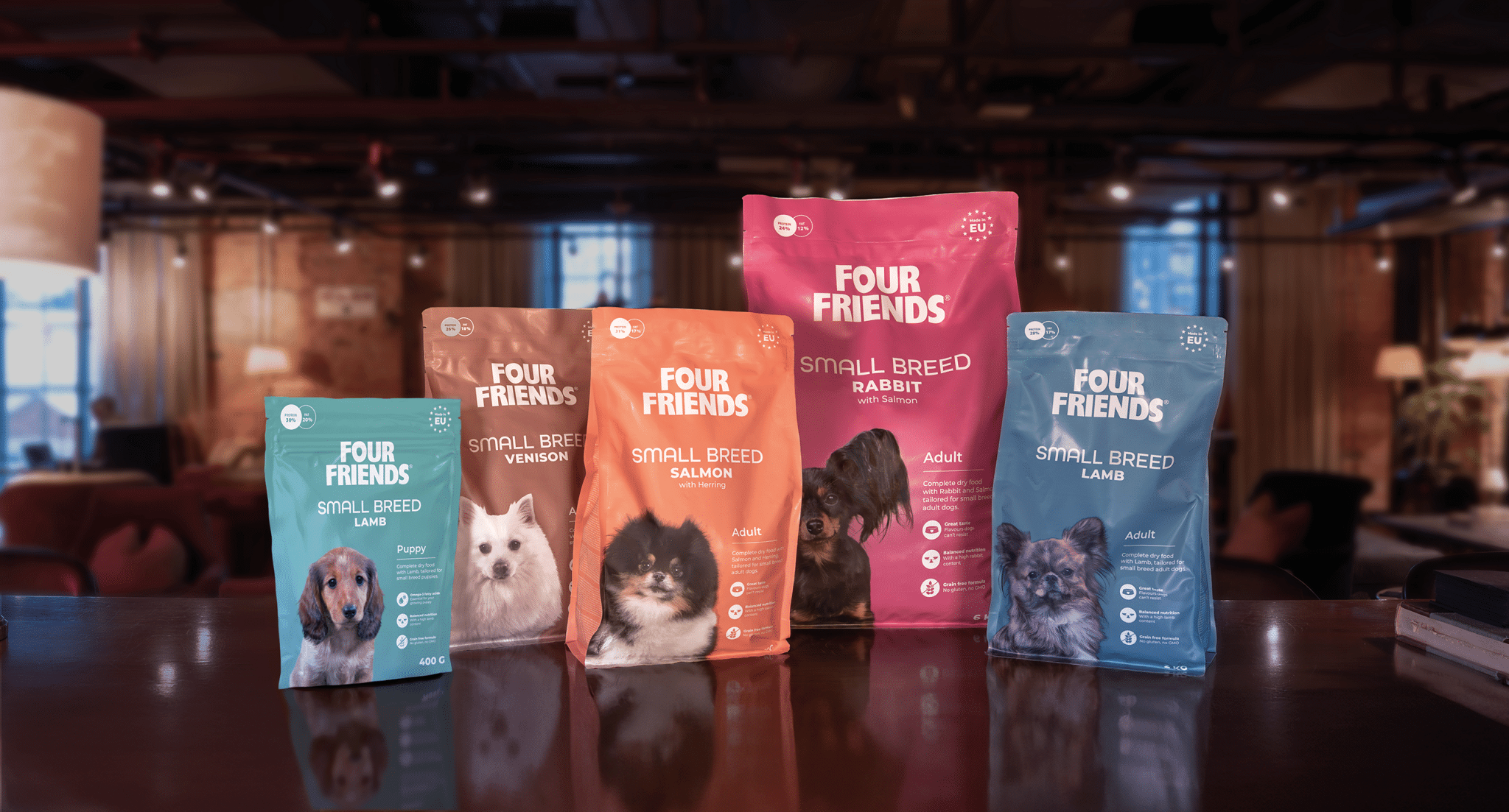 Fem torrfoderpåsar med texten FourFriends Small Breed i färgerna turkos, brun, orange, rosa och blå uppställda bredvid varandra på ett bord.